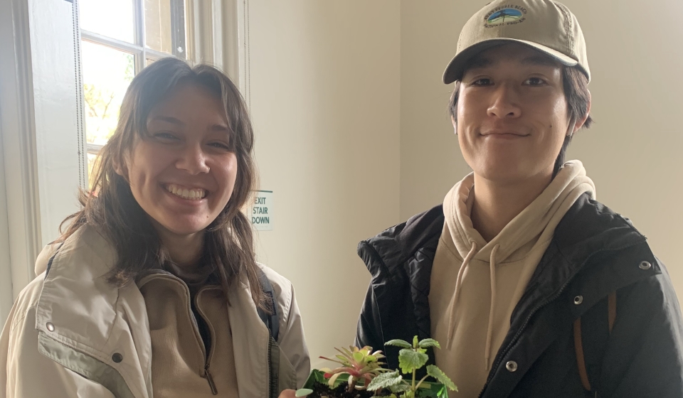 Two participants from the Bring Your Own Pot Event hold up their potted plant.